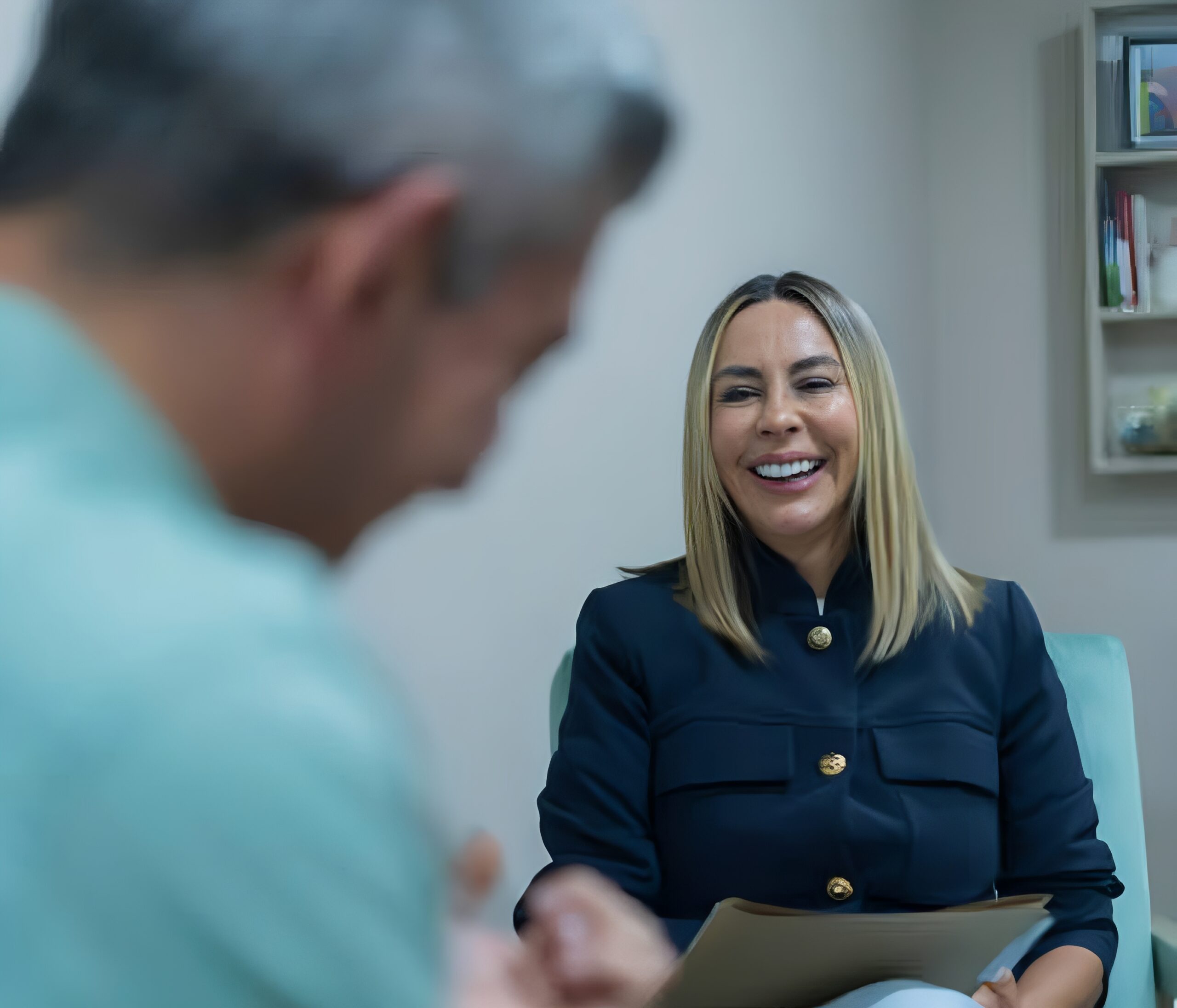 Smiling woman holding clipboard in conversation.