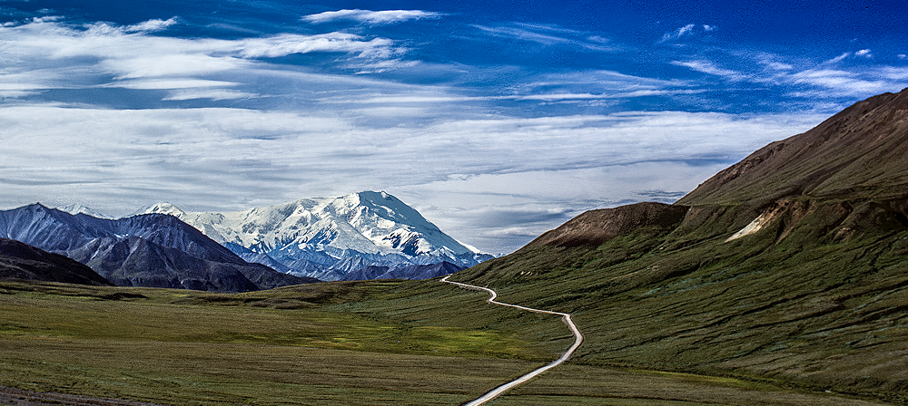 Mountain landscape with winding road and clouds.
