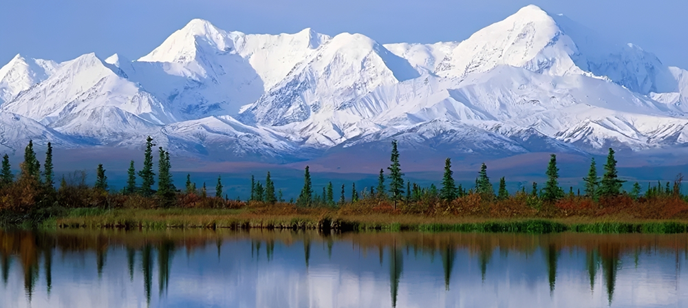 Snowy mountains reflected in calm lake.
