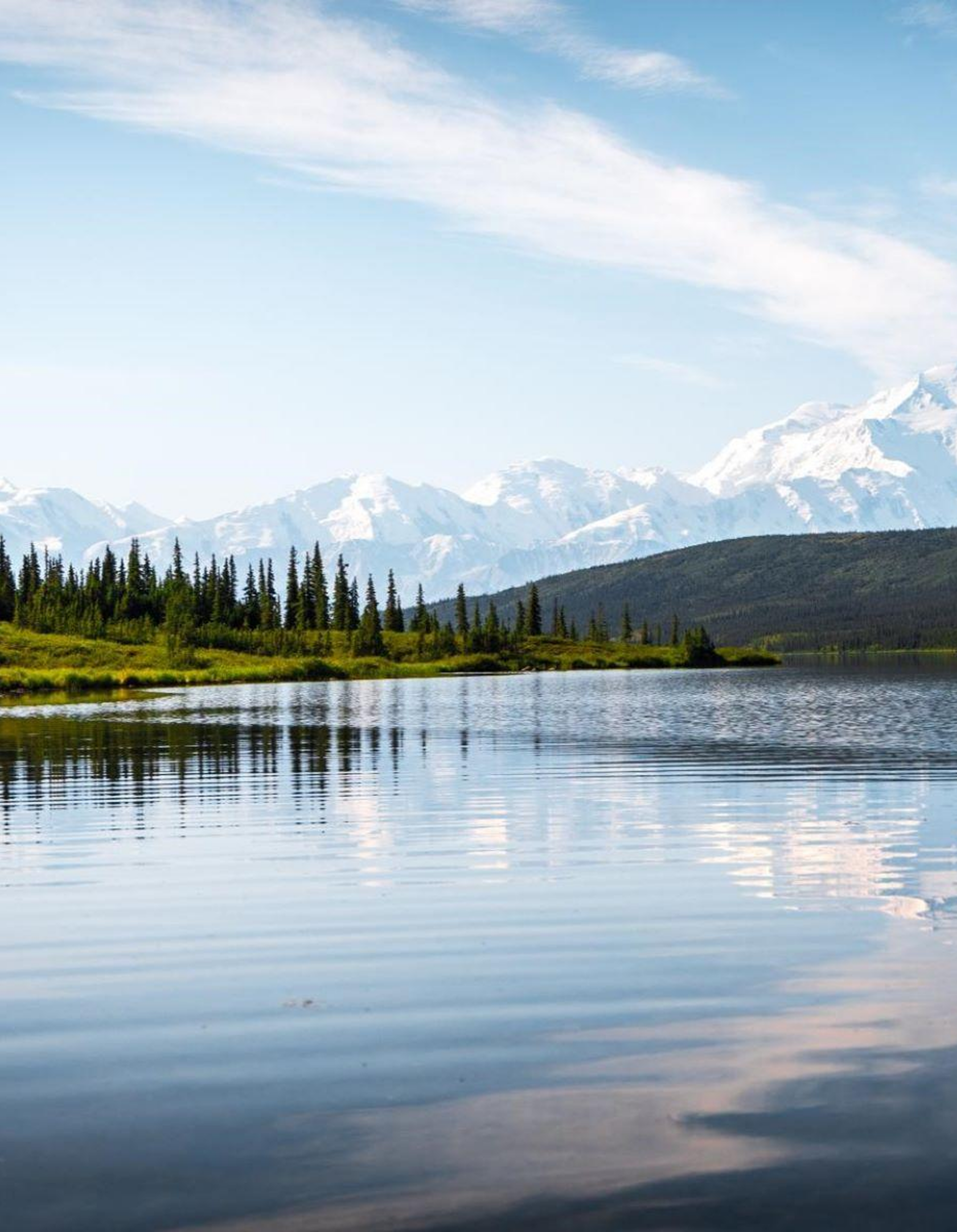 Mountain lake with forest and snowy peaks.