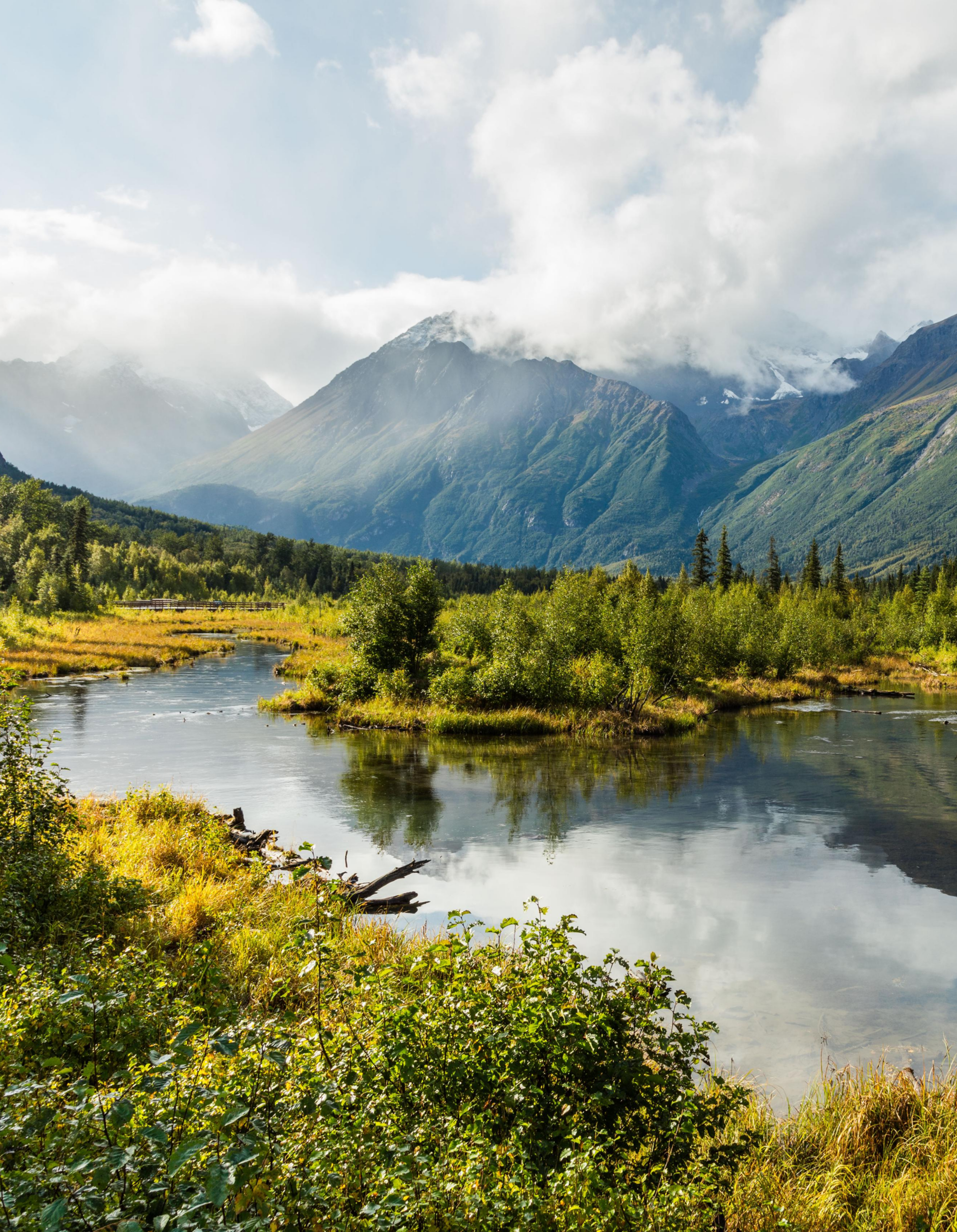 Mountain landscape with river and cloudy sky.