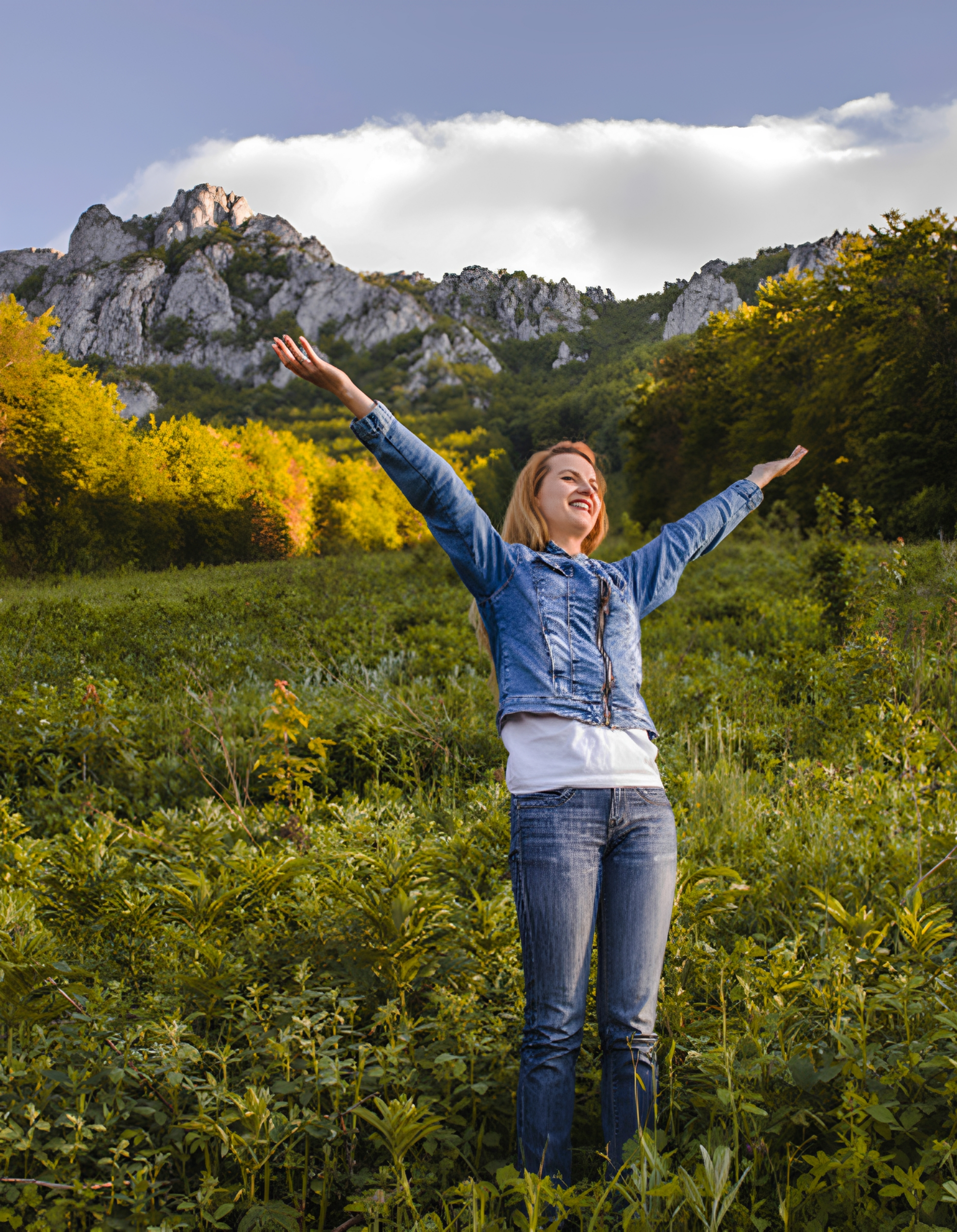 Woman joyfully standing in scenic mountain landscape.