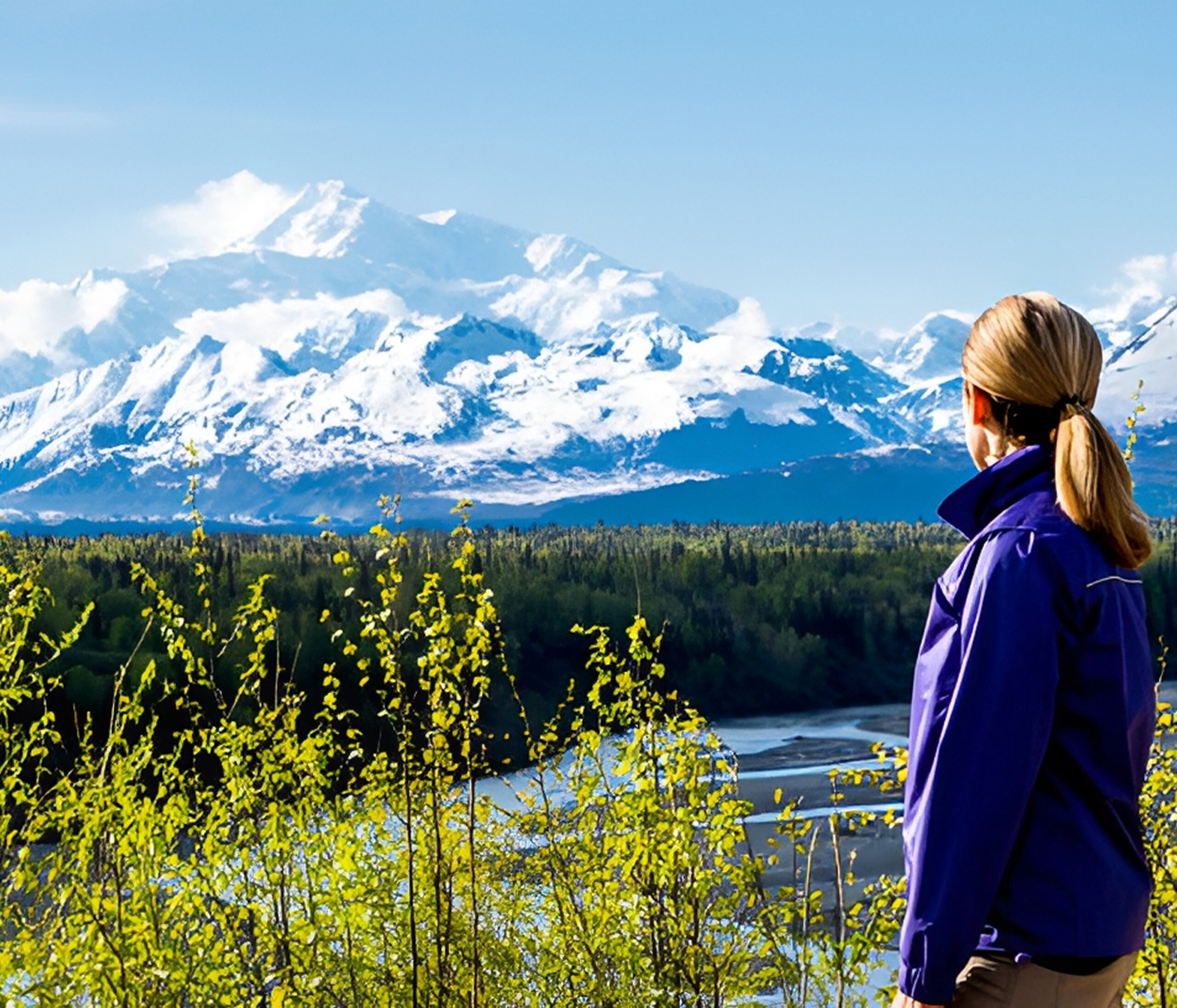 Person admiring snowy mountain landscape and river.