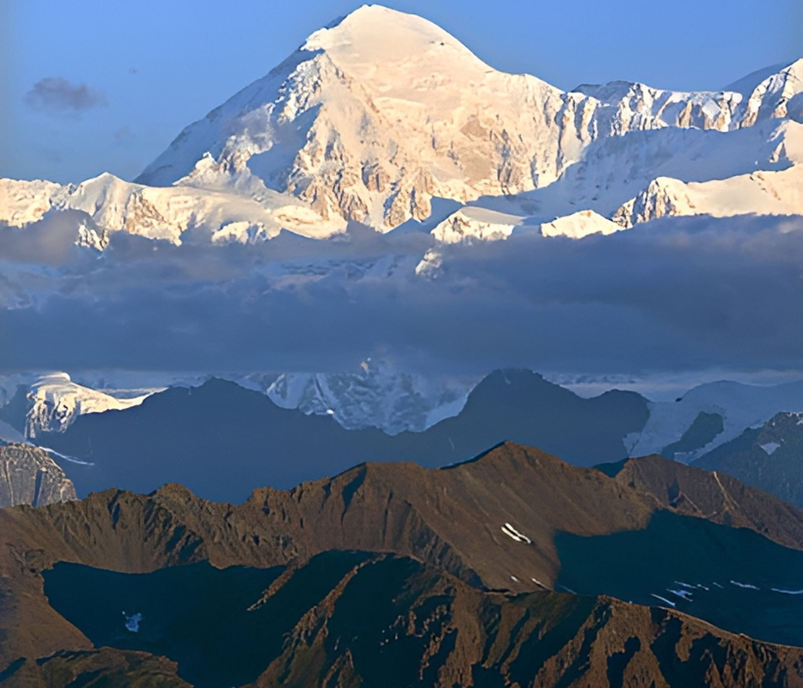 Snow-capped mountain peak above rocky terrain.