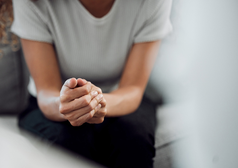 Person sitting with hands clasped together.
