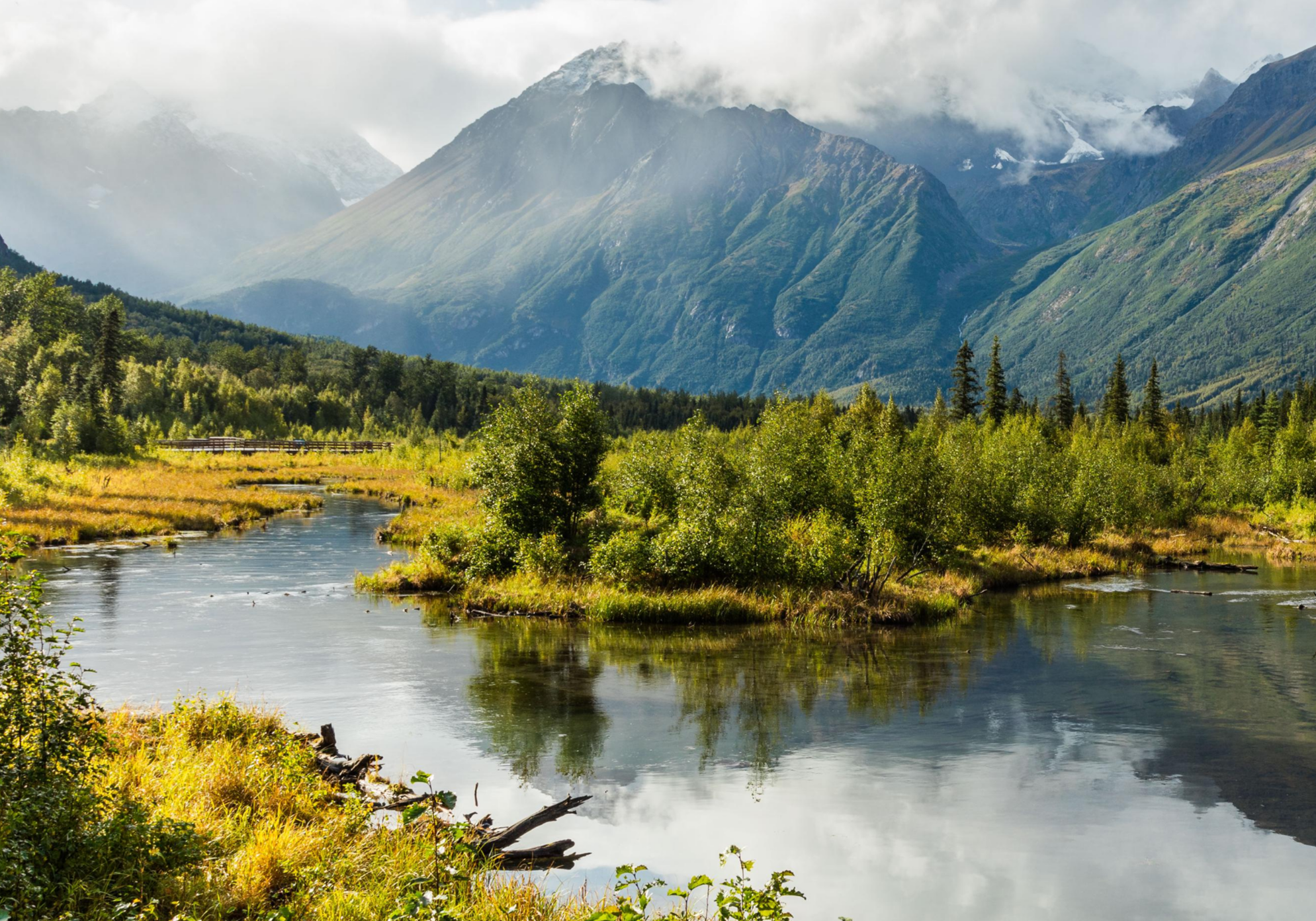 Mountain landscape with river and cloudy sky.
